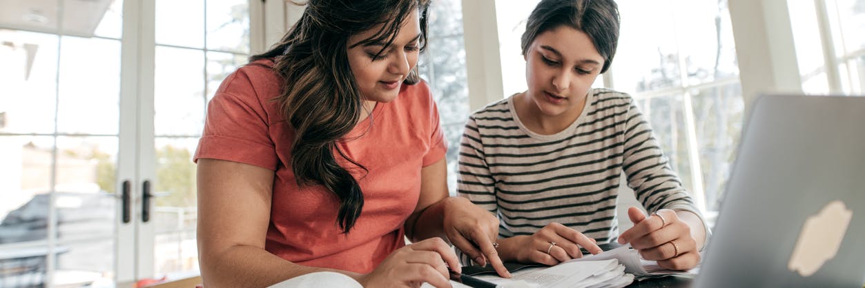 Parent helping child with her homework, using math resources on their computer to help them. 