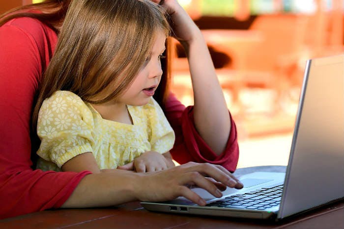Parent sitting with child working together on a laptop.