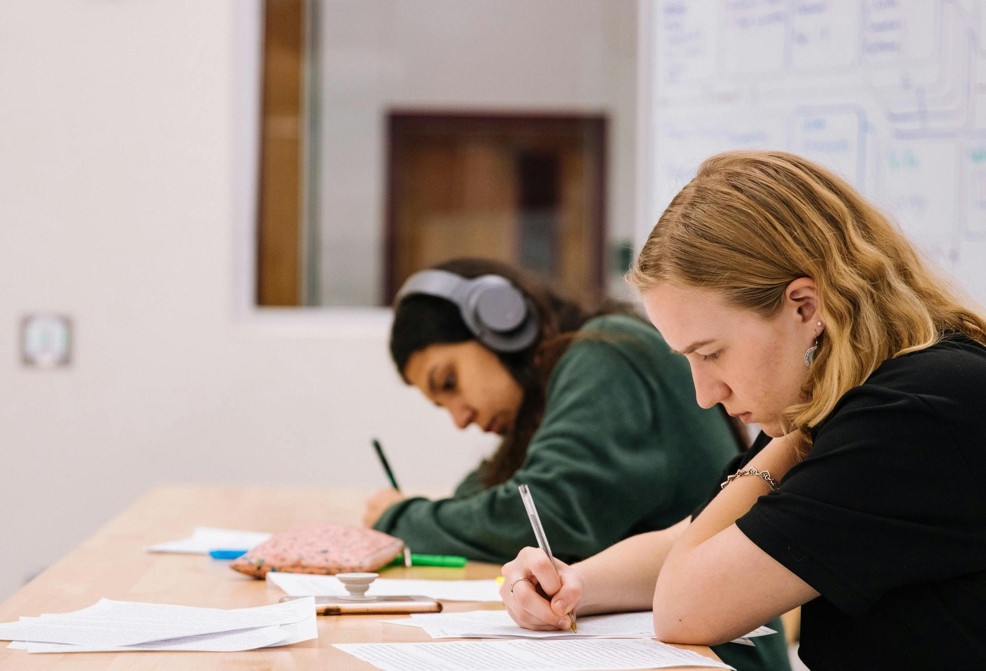 Two students write a test in a classroom.