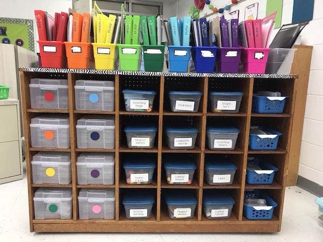 Color-coded bookshelf with different colored binders and bins.
