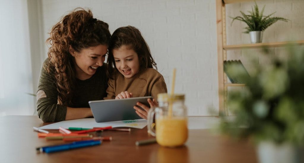 A mother and her child playing on a tablet together.