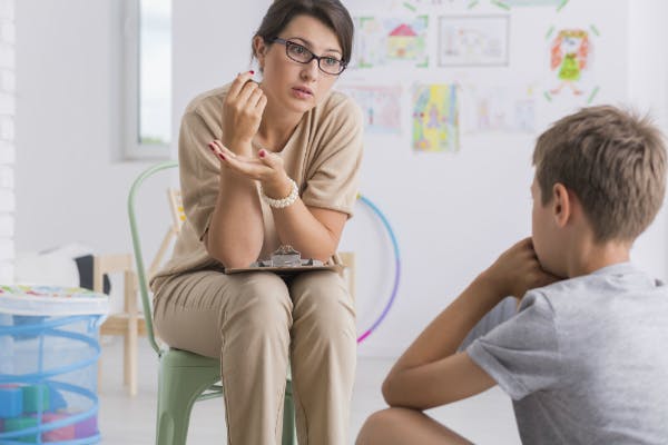 A teacher sits down with a misbehaving student, talking to him about his behavior as one of her classroom management strategies.