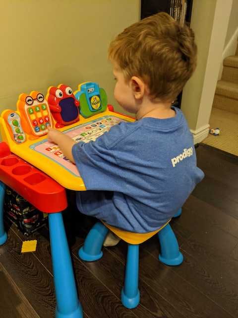 Toddler sitting at play desk.