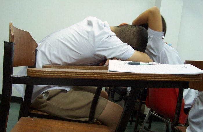 A child, frustrated with math, places their head on their desk.