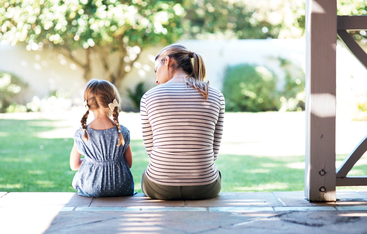 Mother talking to her daughter about her school day as they sit together on the patio.