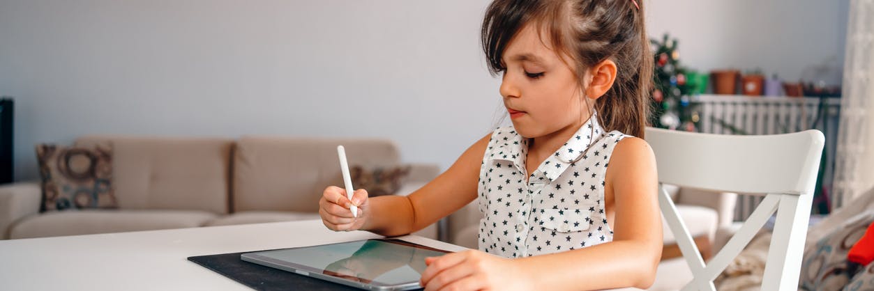 A young girl sitting at a table preparing for first grade learning.