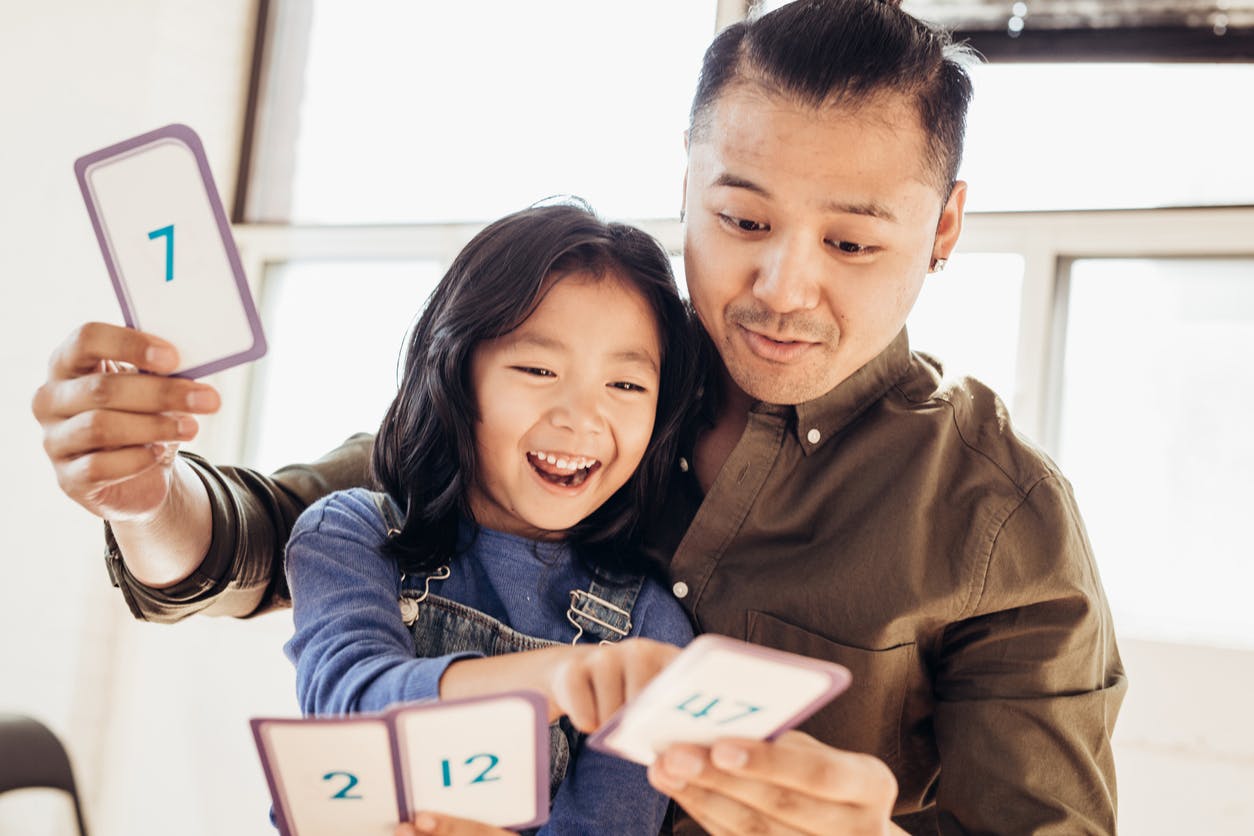 Parent helping his child with math, using flashcards as a helpful resource.