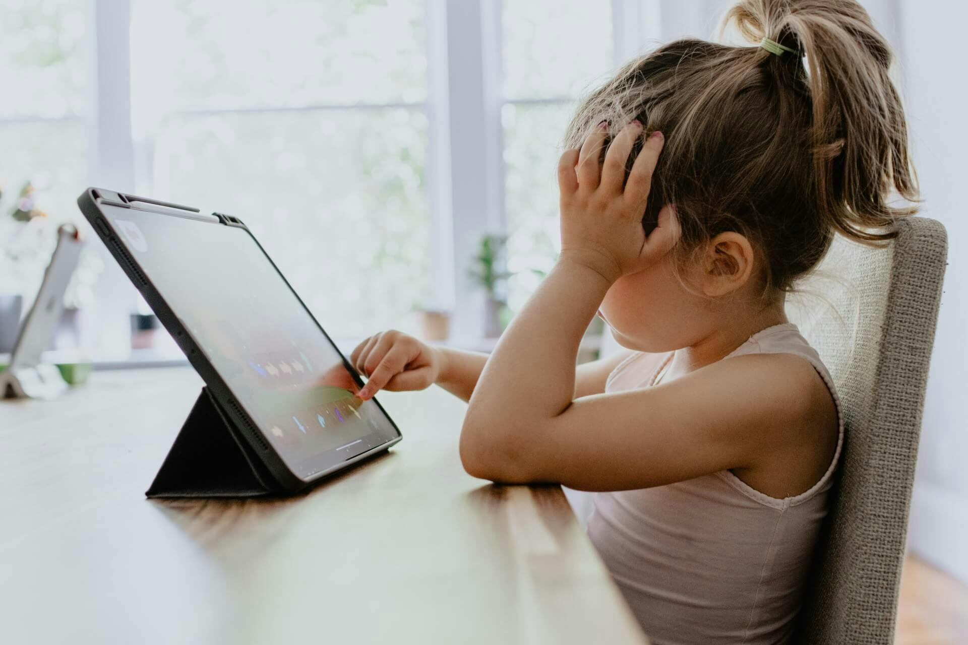 A young girl spends time playing games on her tablet.