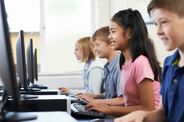 Four children each working in front of a computer in class.