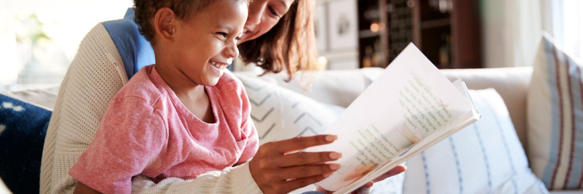 Mother and son sit on a couch at home and practice first grade reading.