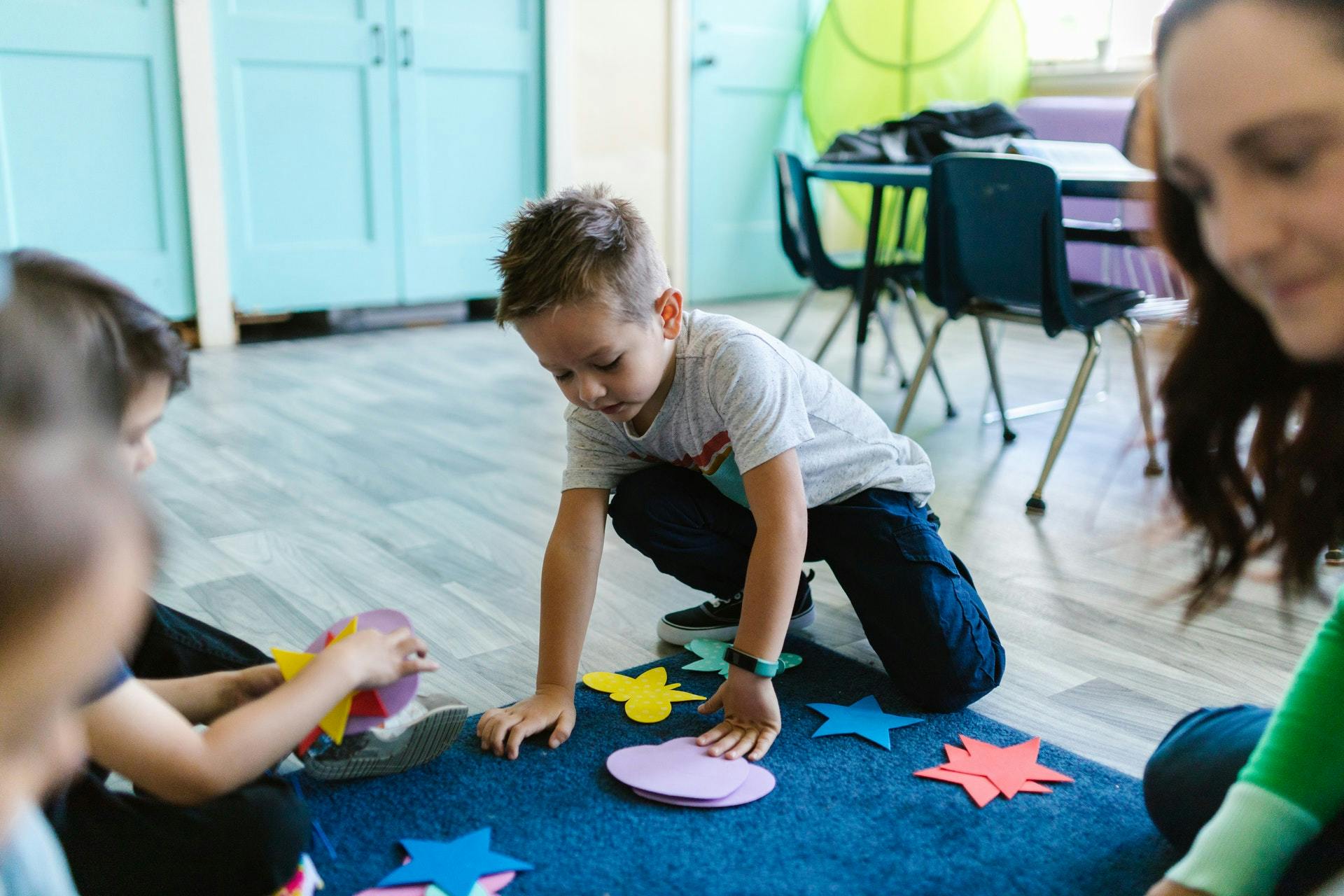 Students play with shapes on a mat in the classroom during a geometry activity