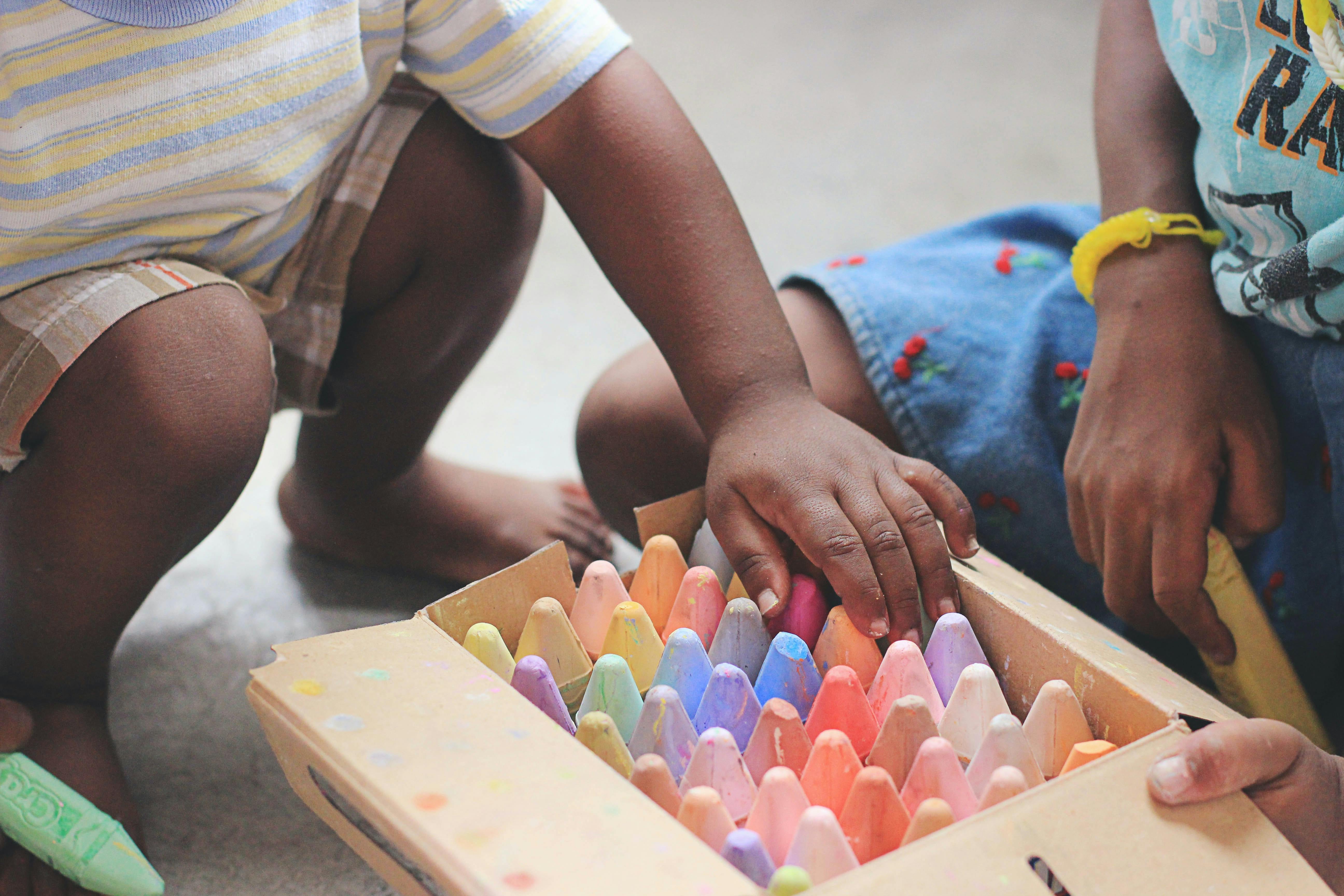 Two children sharing sidewalk chalk.