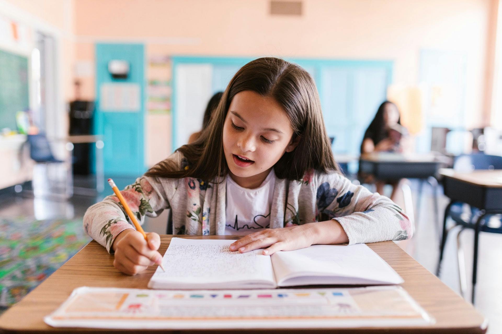 Young girl sits at a desk and works on an assignment in a positive learning environment.