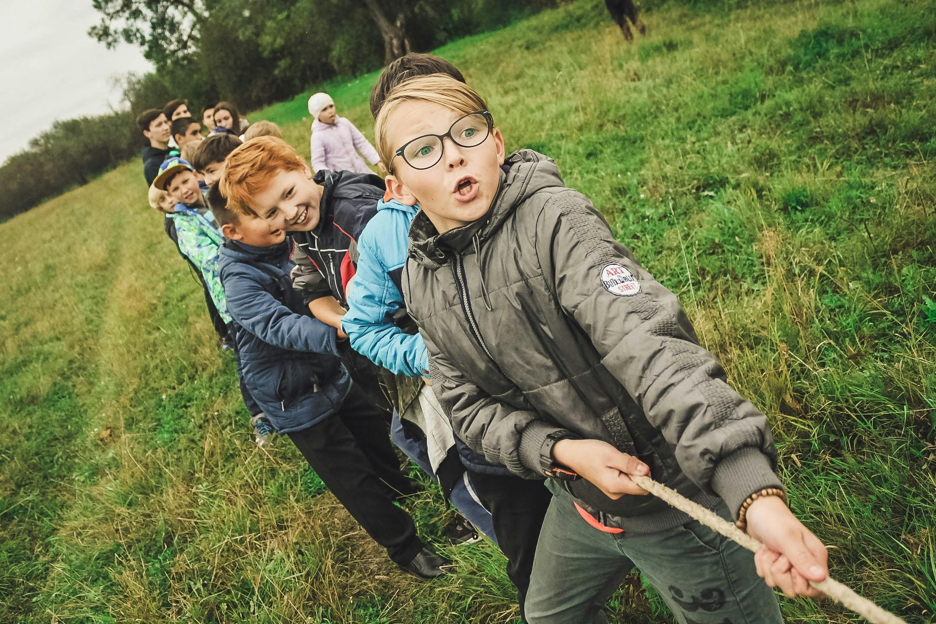 A group of students plays a team-building game of tug-of-war outside.