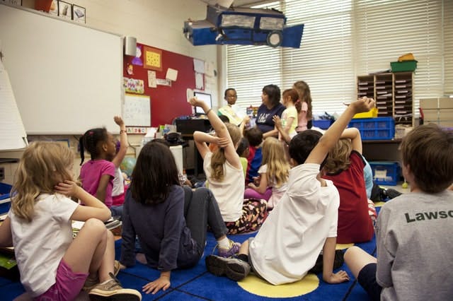 Students sitting on the carpet in a classroom.