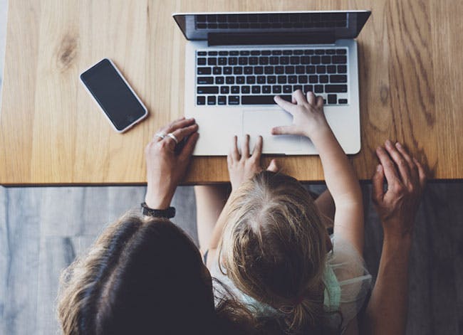 Daughter sits with mother using laptop.