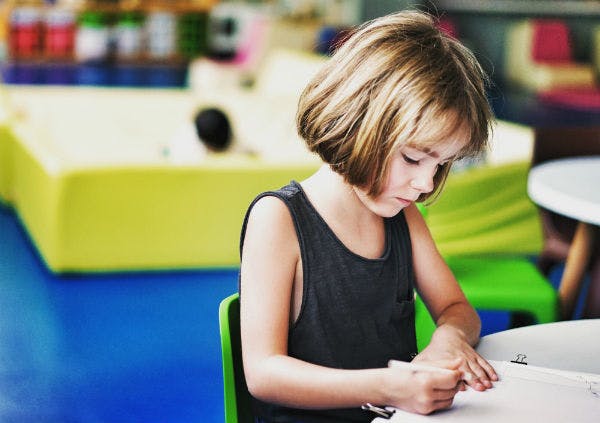 A young girl is sitting and working on her homework