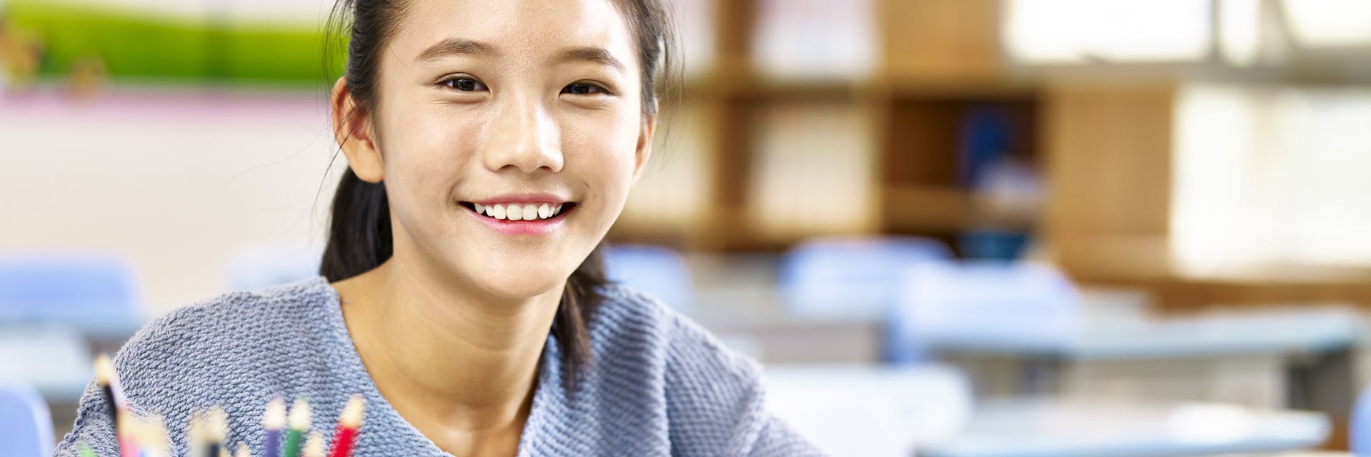 Young girl sits in a classroom writing a story using the key elements of a story.