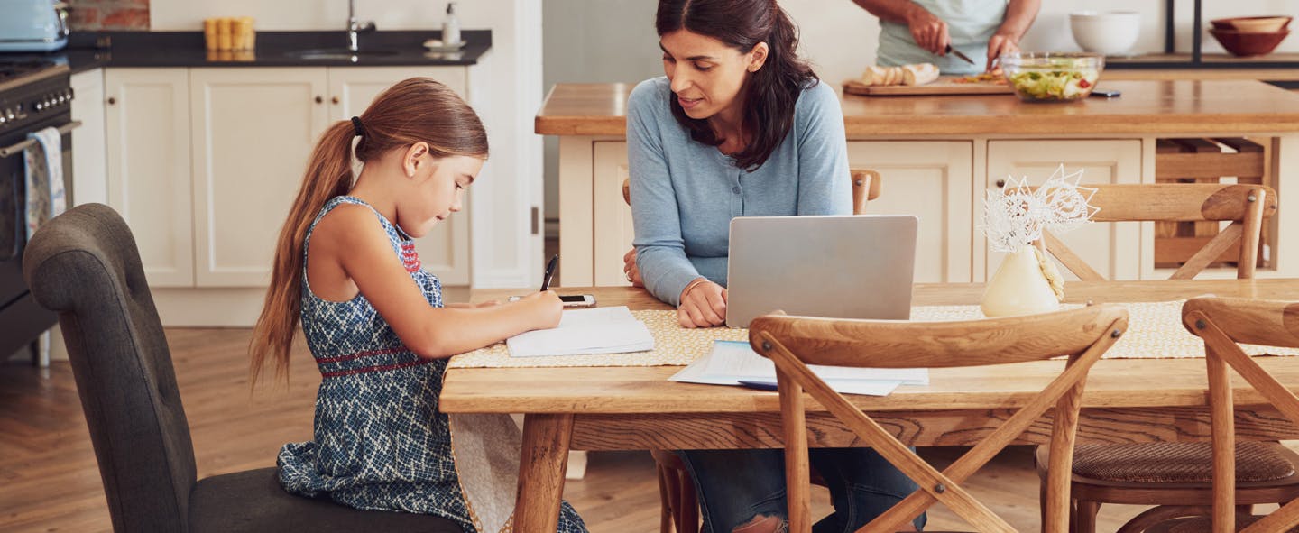 Child doing homework with parent in kitchen table