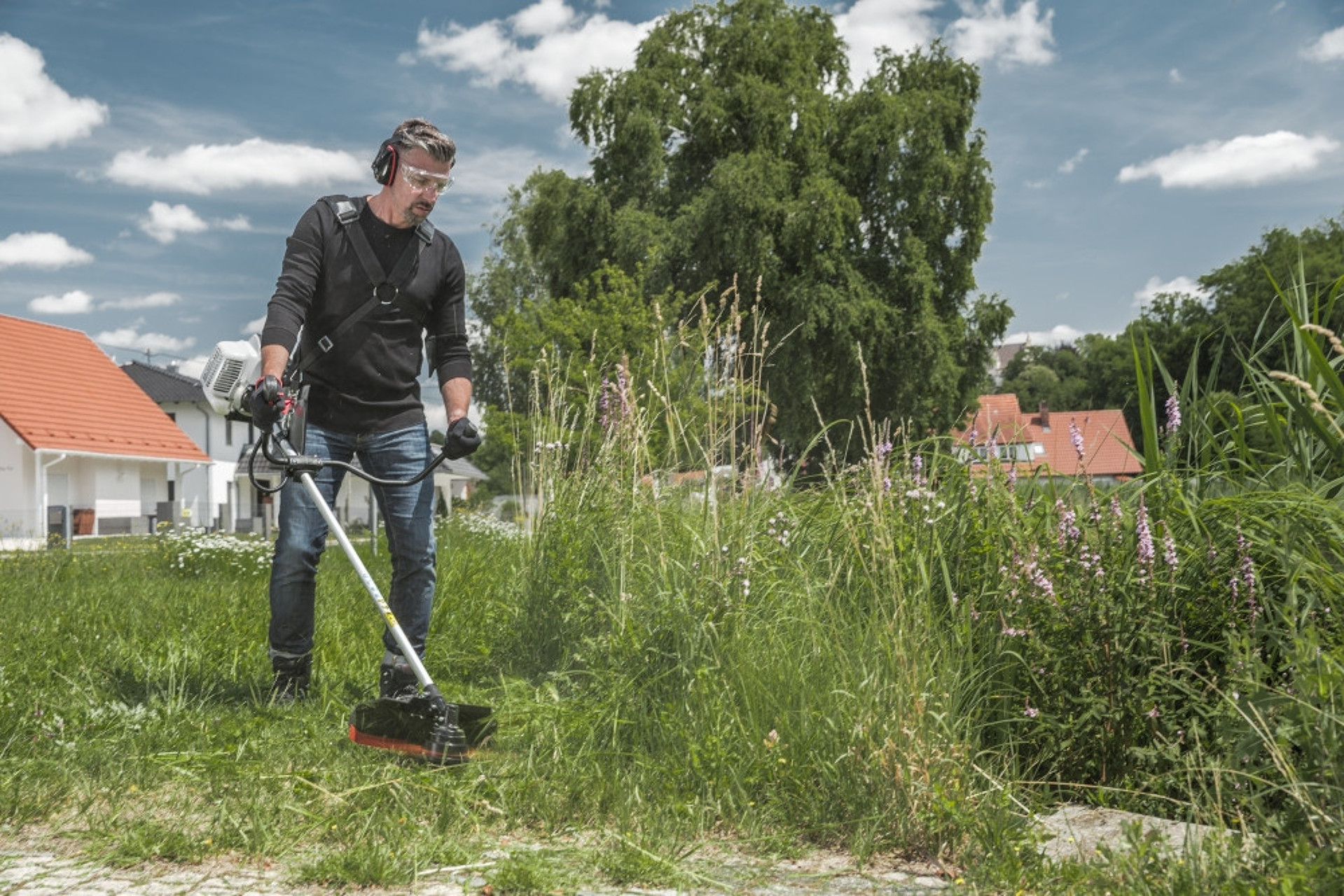 Person trimmer høyt gress med god teknikk