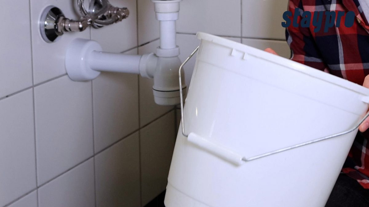 Person holder en bøtte under vasken