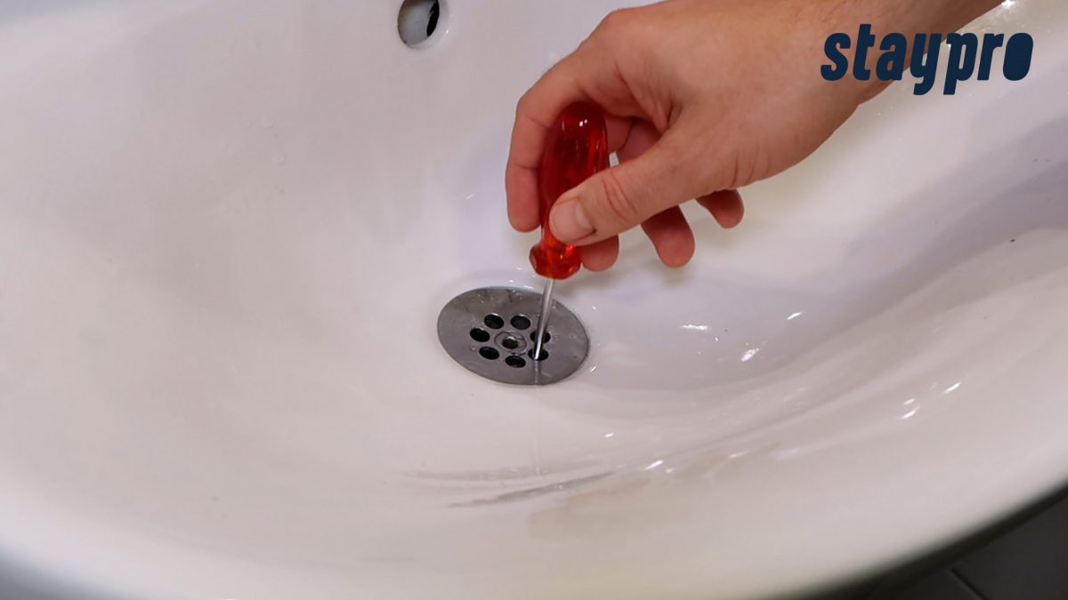 Person bruker noe langt og smalt for å rengjøre silen