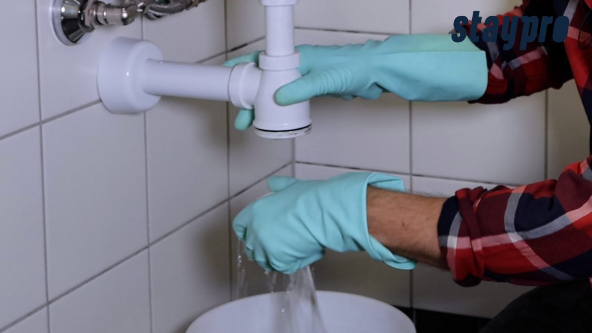 Person skrur av bunnen på vannlåsen