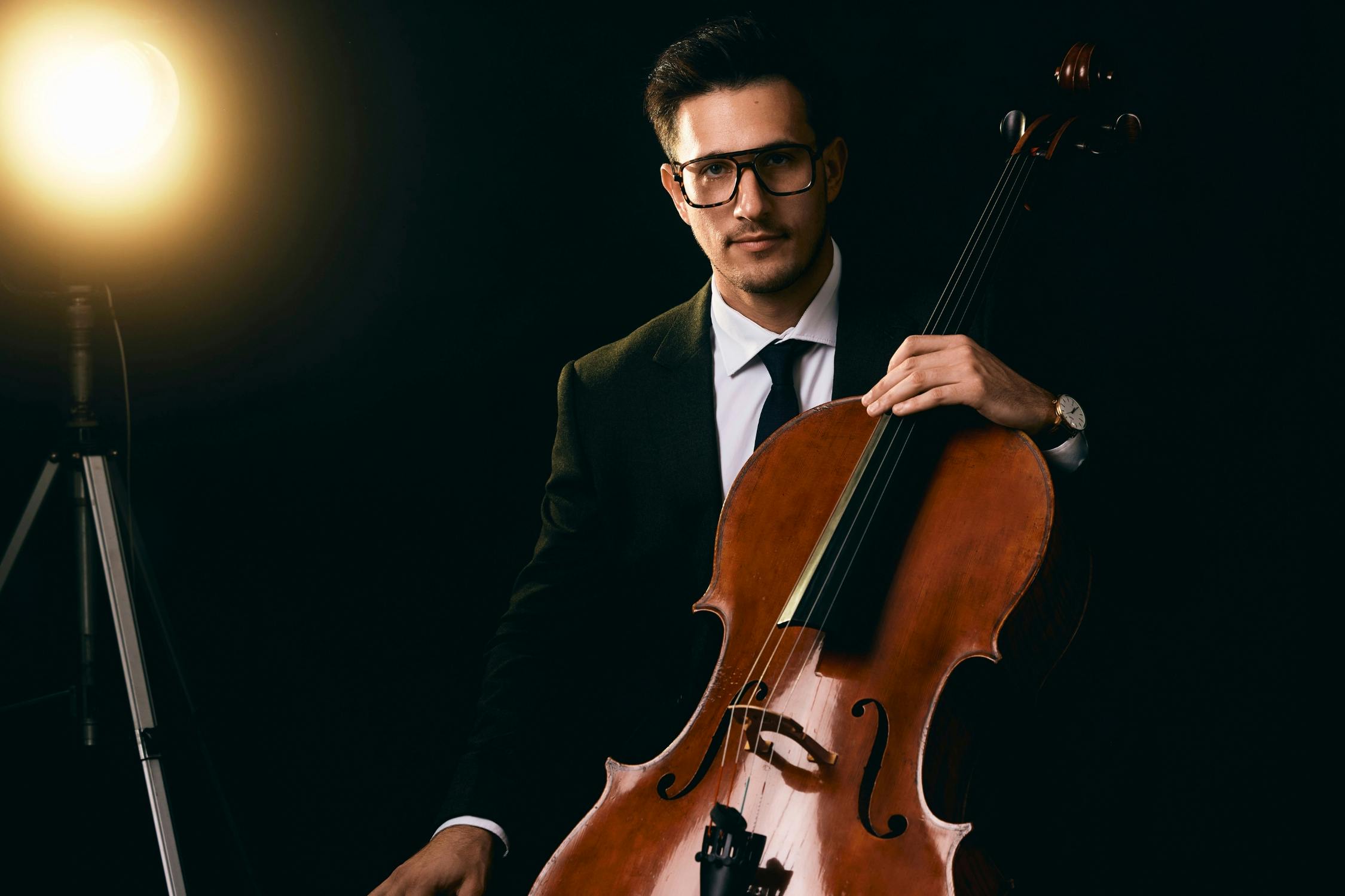 Frontal cello pose under spotlight