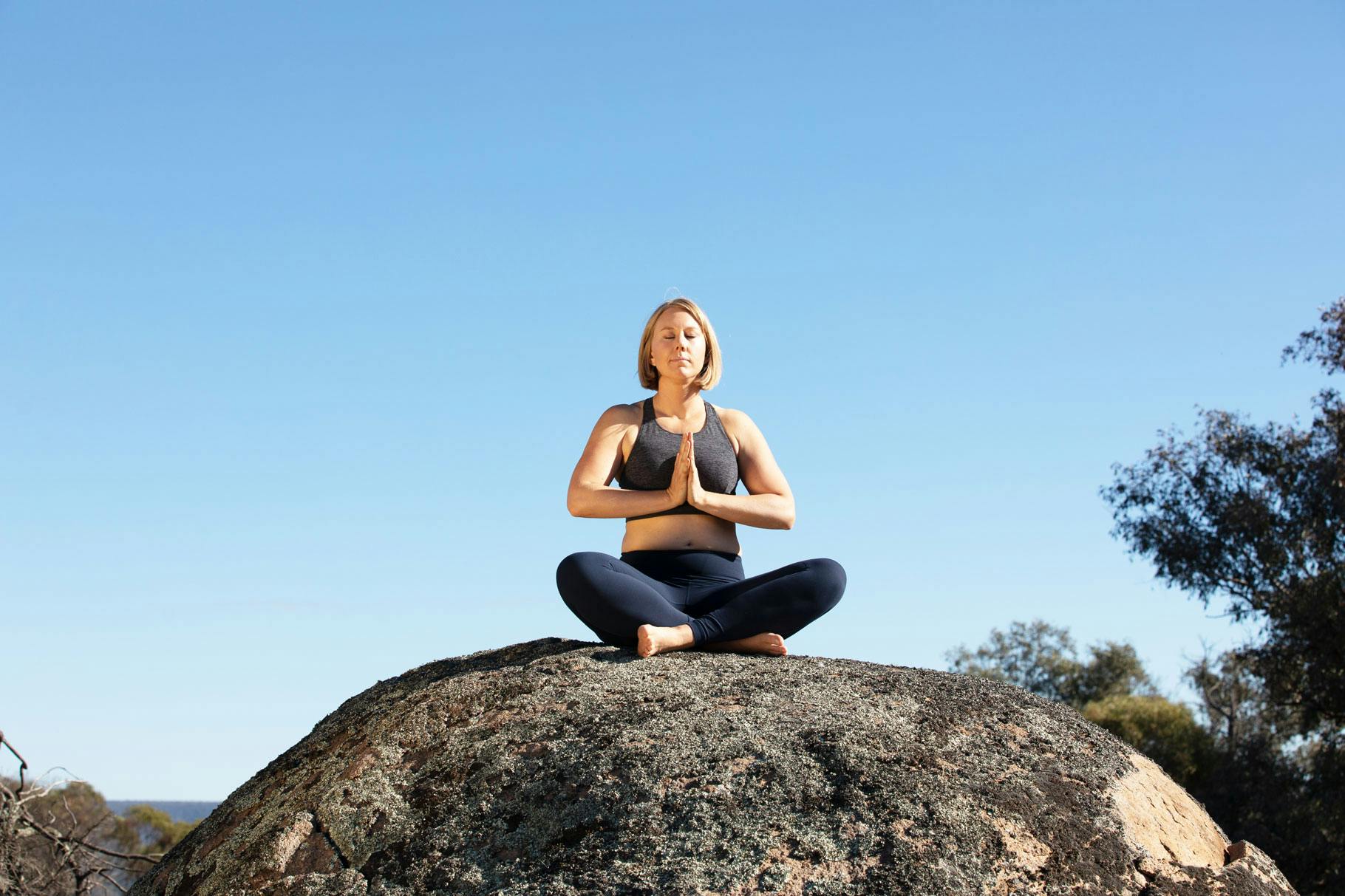 Camilla Sinclair on rock in prayer position