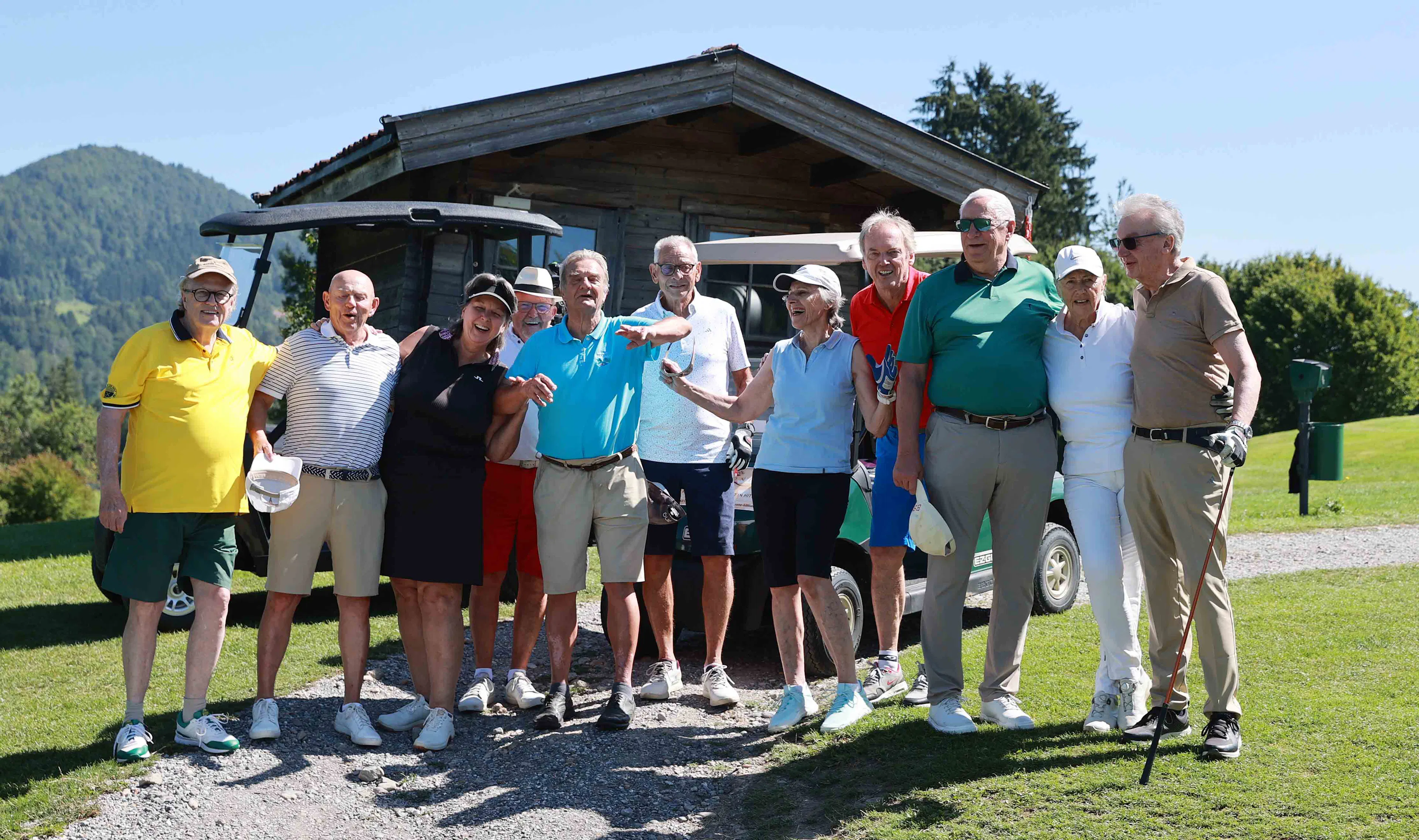 Seniorengruppe posiert lächelnd auf dem Golfplatz neben Golfcart