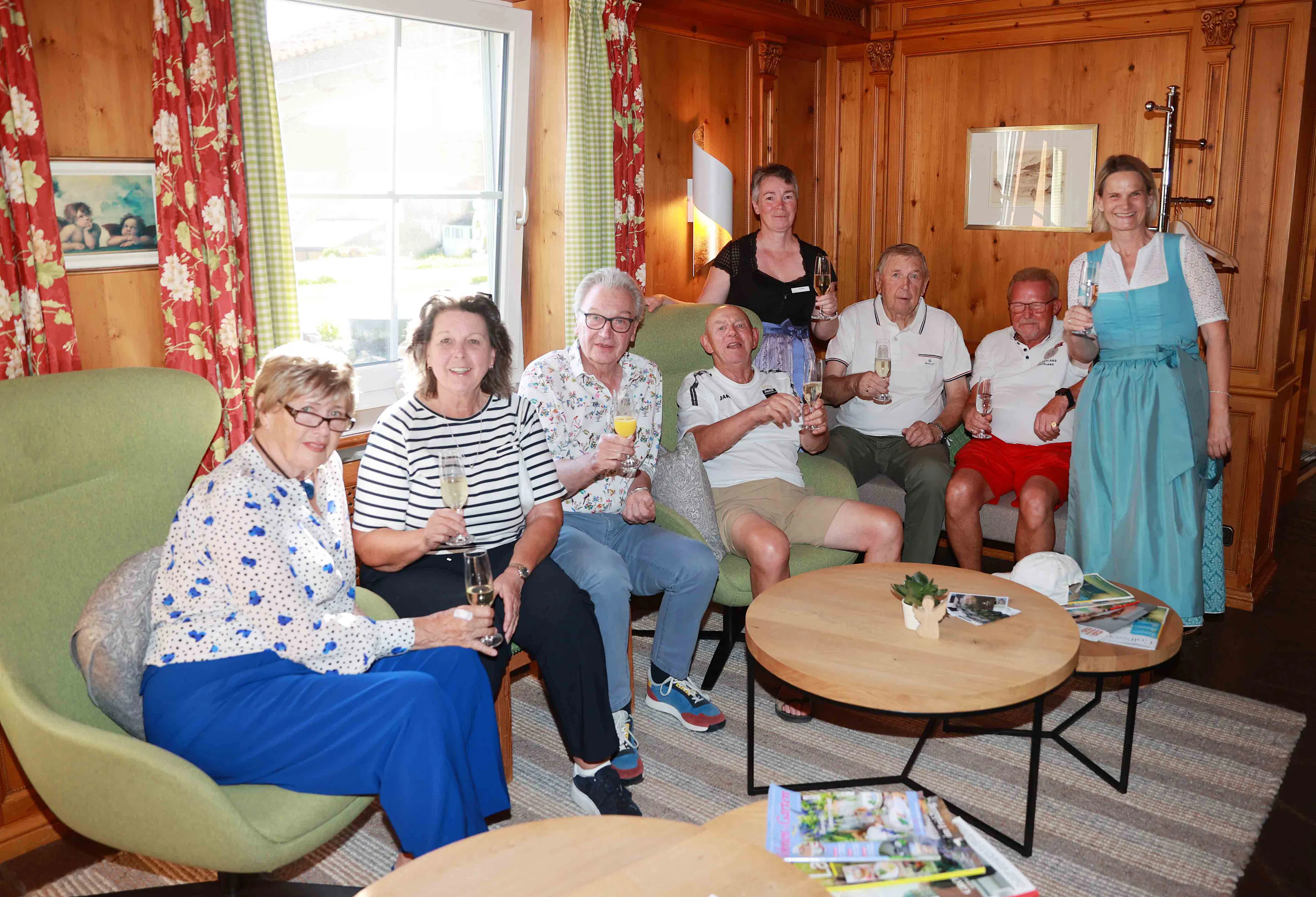 Gruppe sitzt mit Sektgläsern in einer gemütlichen Holz-Lounge