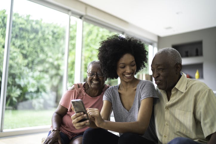 Neta e seus avós sorrindo e olhando para o celular