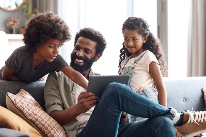 família sorri enquanto interage com um tablet