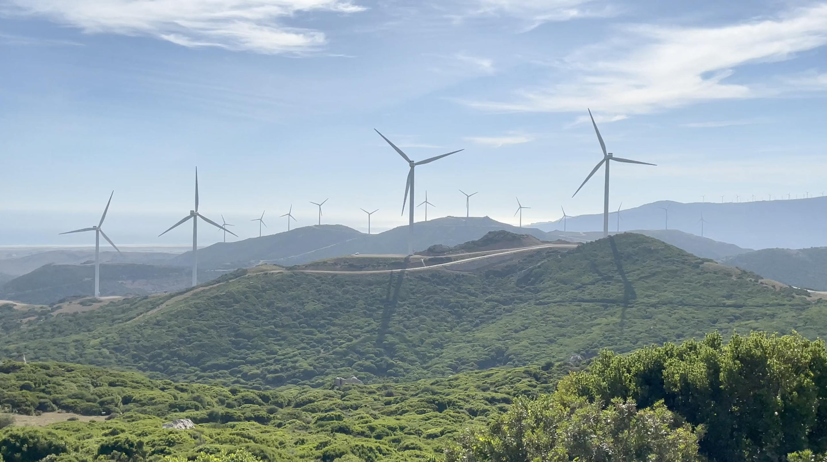 Photo of large wind turbines on green, rolling hills