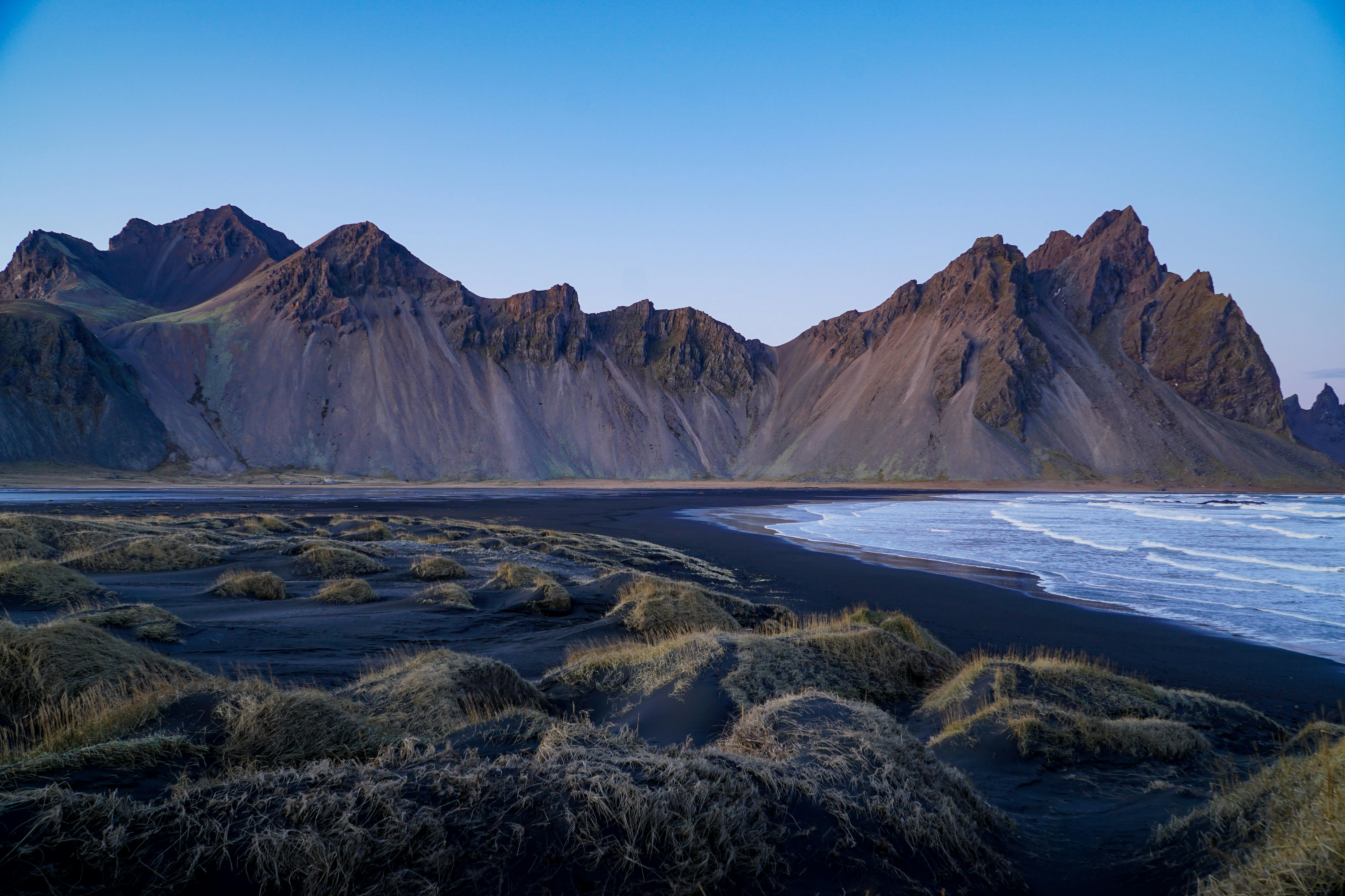 View of mountainous landscape behind black sand beach