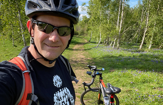 Man in sunglasses with bike in forest smiling at camera