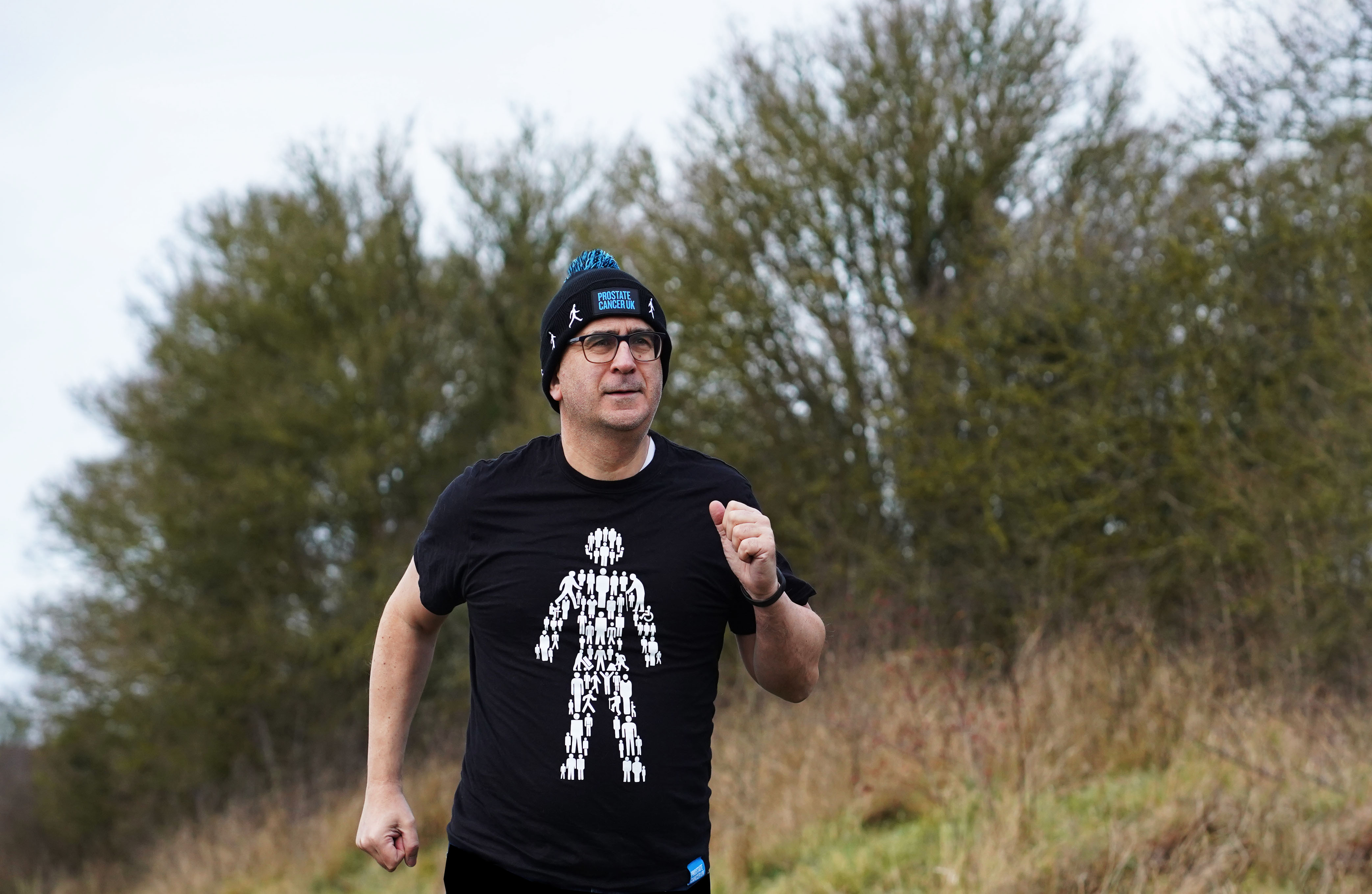 A man running wearing a bobble hat and man of men t-shirt