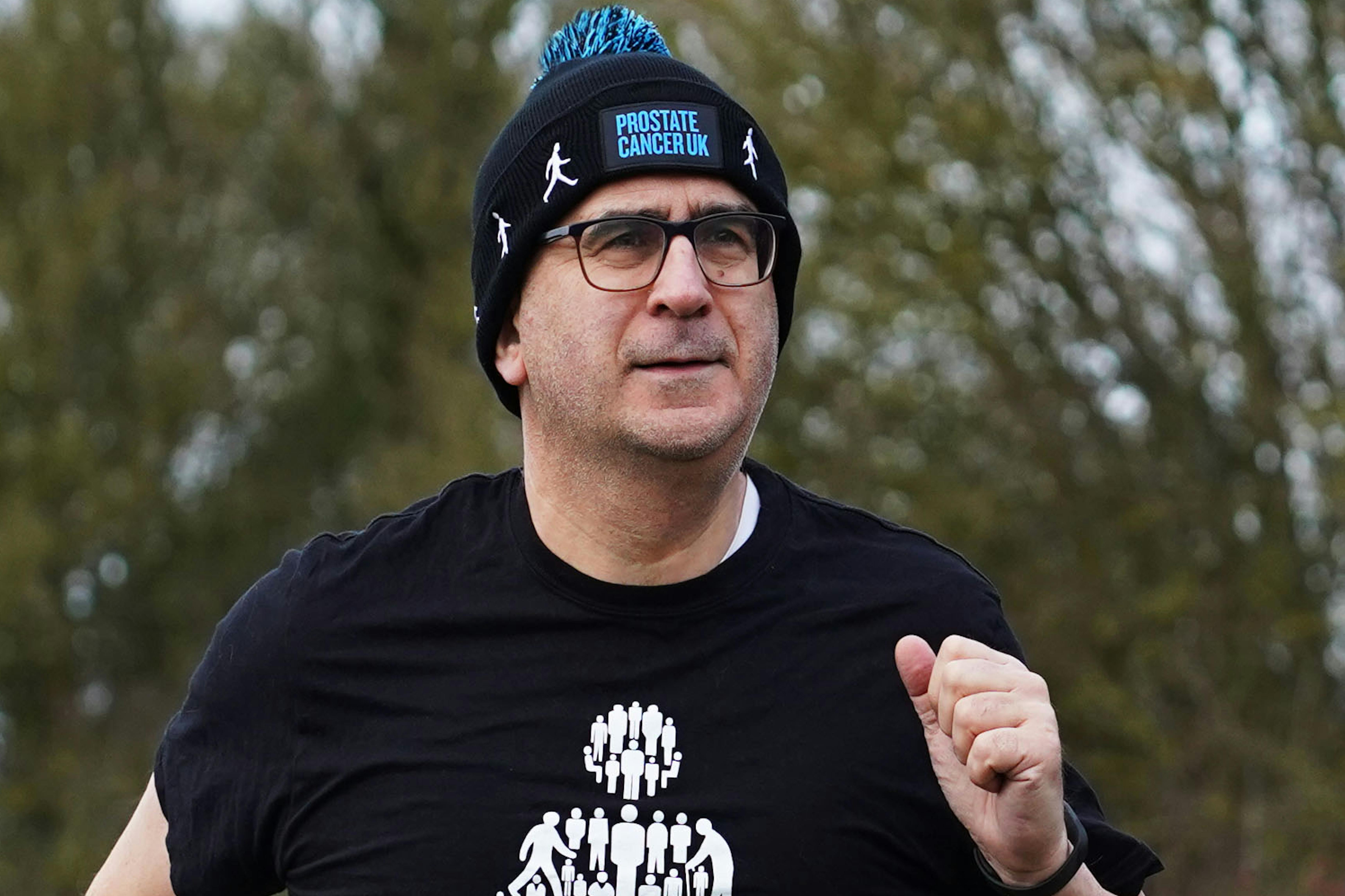 A man running wearing a bobble hat and man of men t-shirt