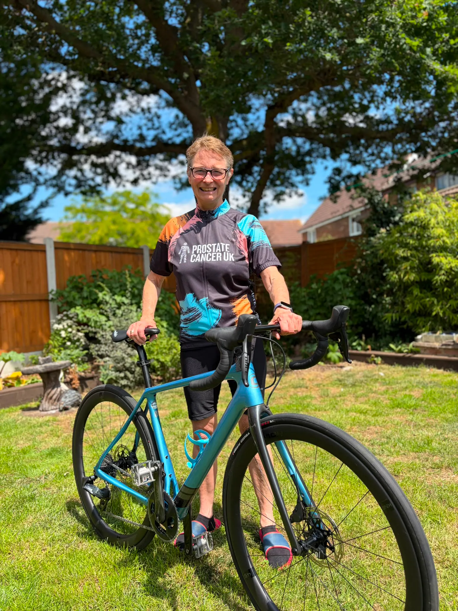 Smiling lady in cycle jersey and standing with bike