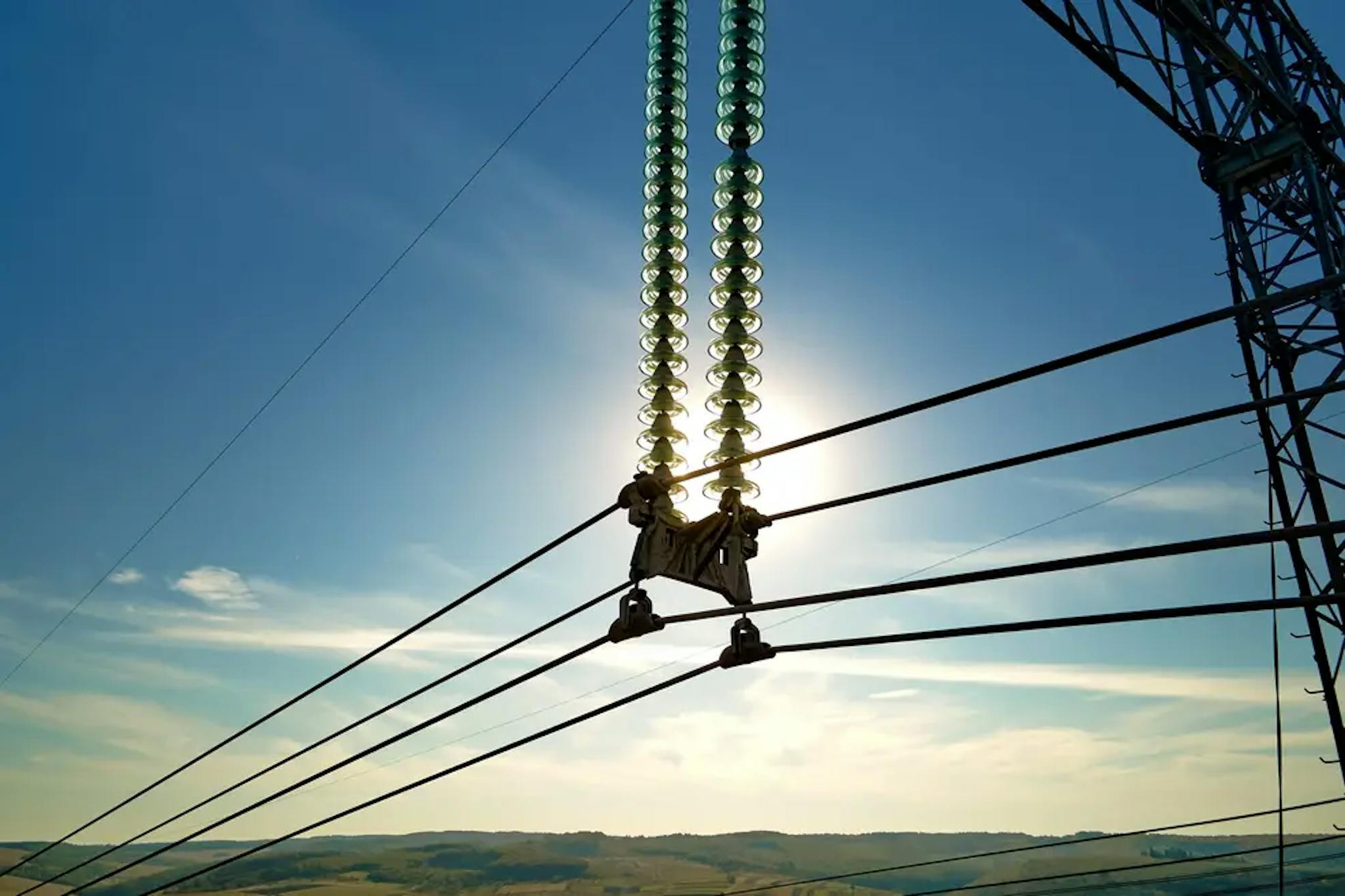 Linie energetyczne wysokiego napięcia na tle zachodzącego słońca