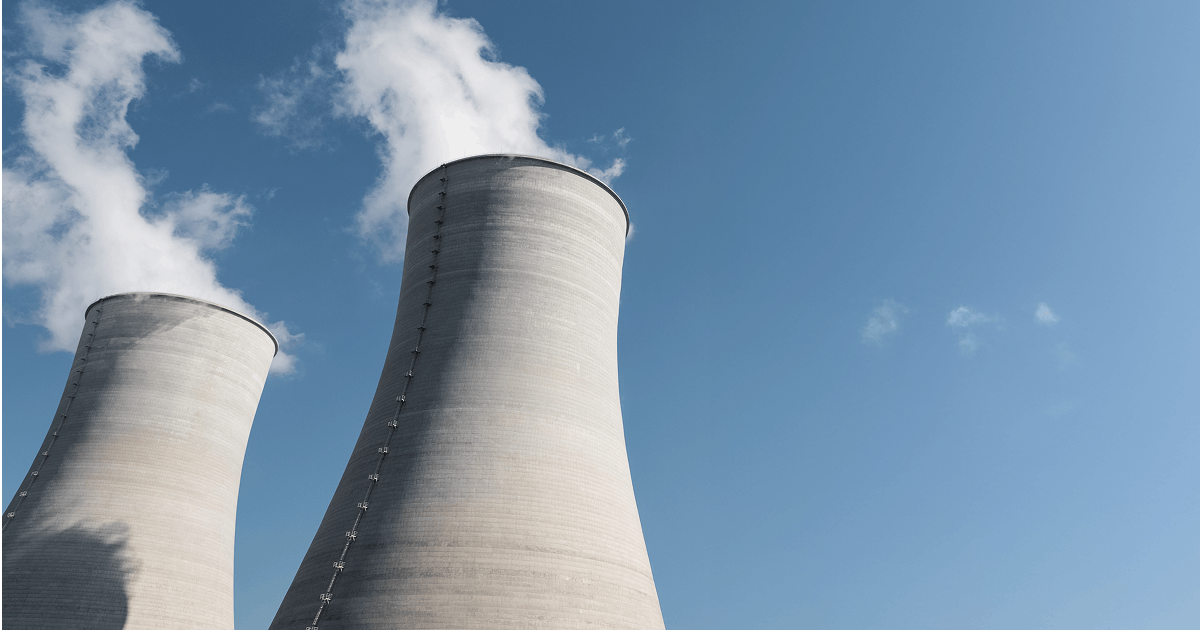 Dwie chłodnie kominowe elektrowni z unoszącą się parą wodną na tle nieba