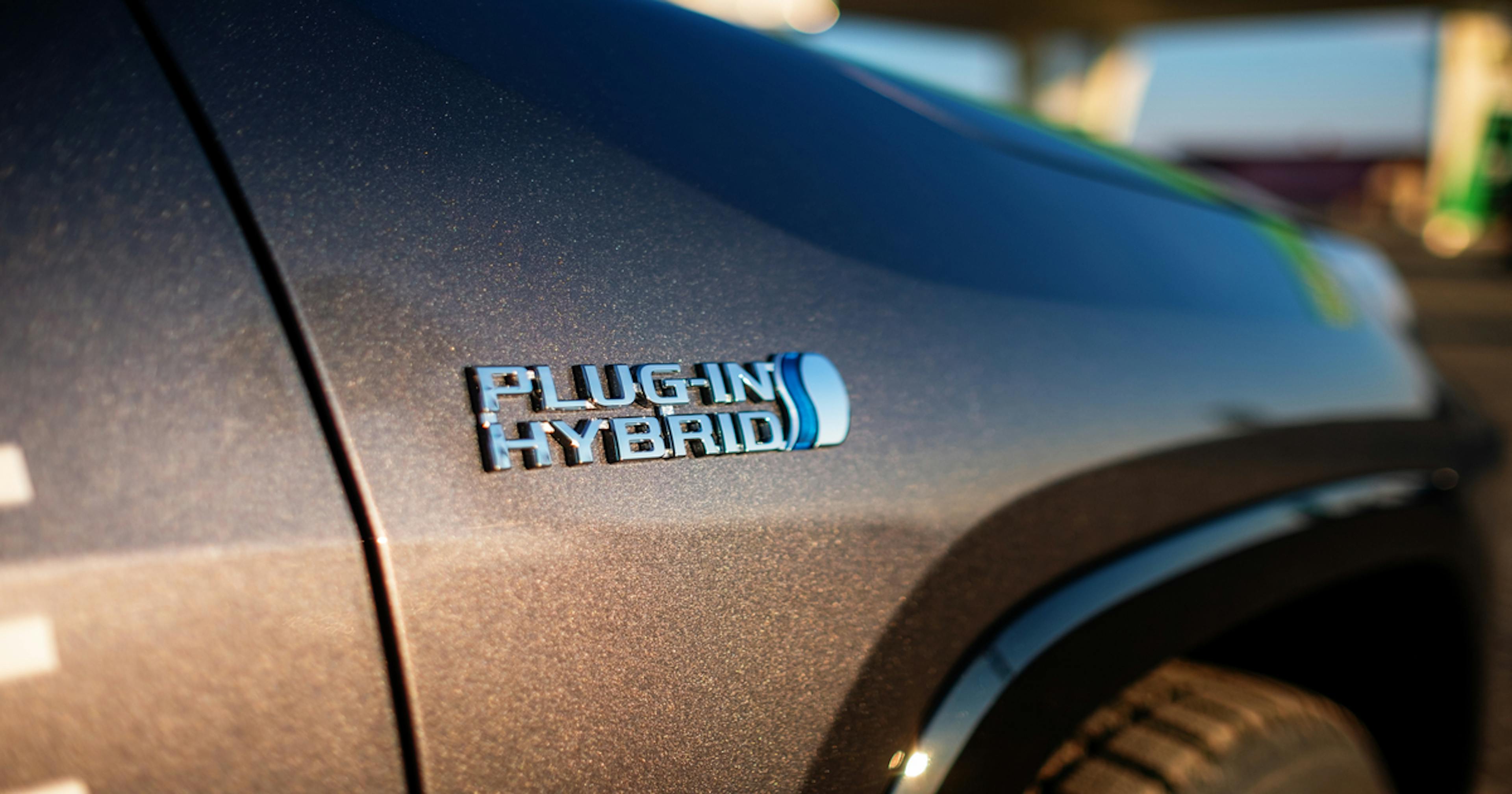 Napis „Plug-in Hybrid” na nadwoziu auta przy stacji ładowania.