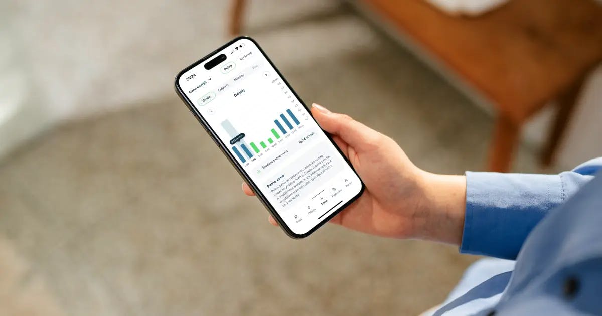 Zdjęcie ręki trzymającej telefon, na którym widać wykres cen w aplikacji Pstryk