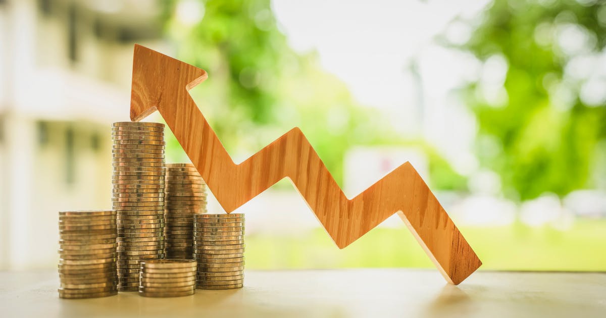 Stosy monet i drewniany wykres w kształcie strzałki