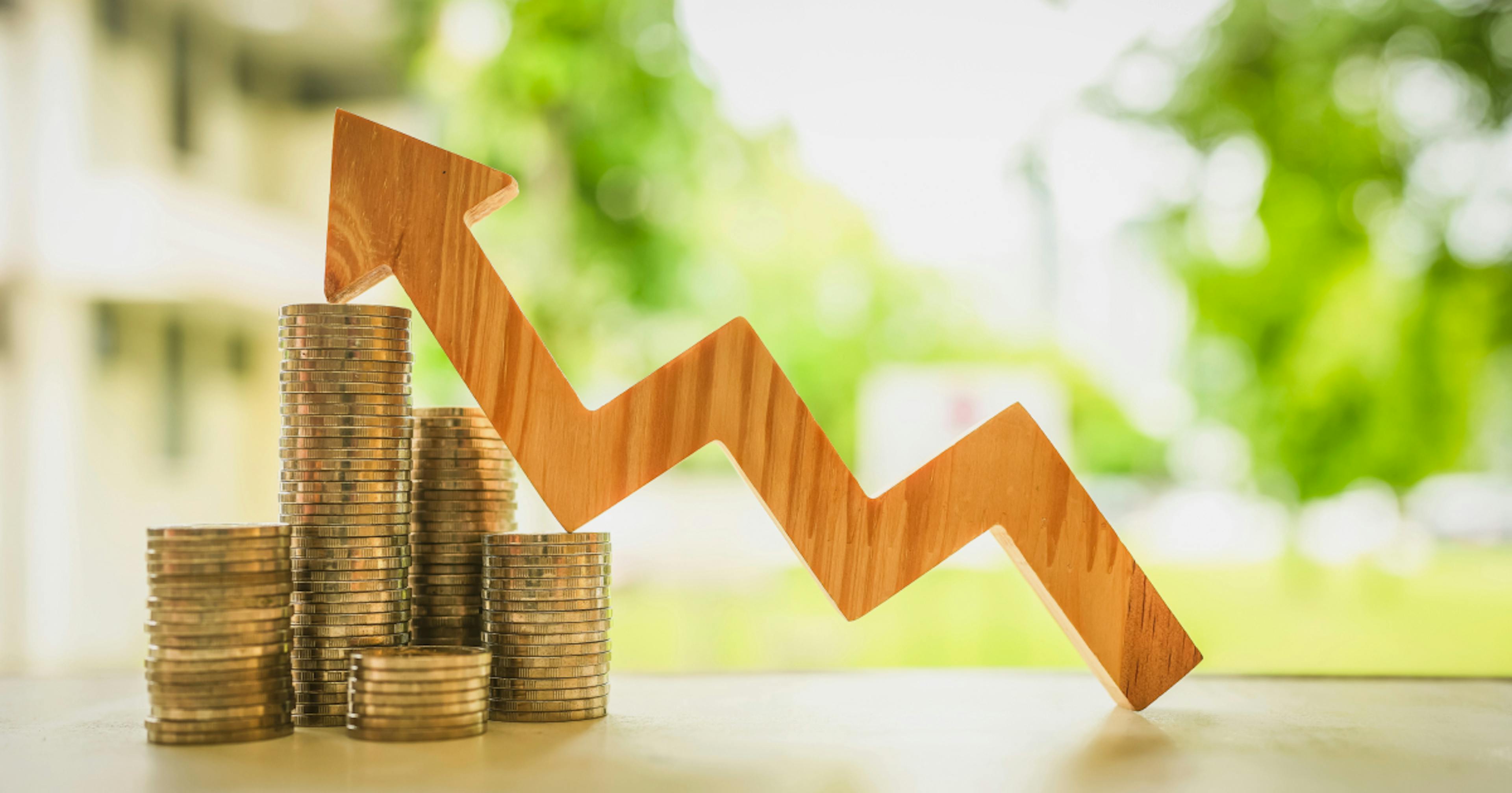 Stosy monet i drewniany wykres w kształcie strzałki