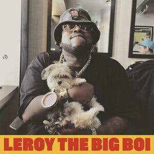 A man holding a dog with the text below: Leroy the big boi