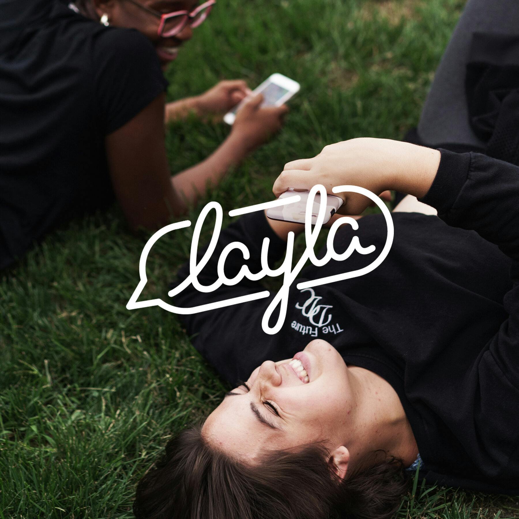 Two ladies laying in the grass with the Layla logo superimposed on the image