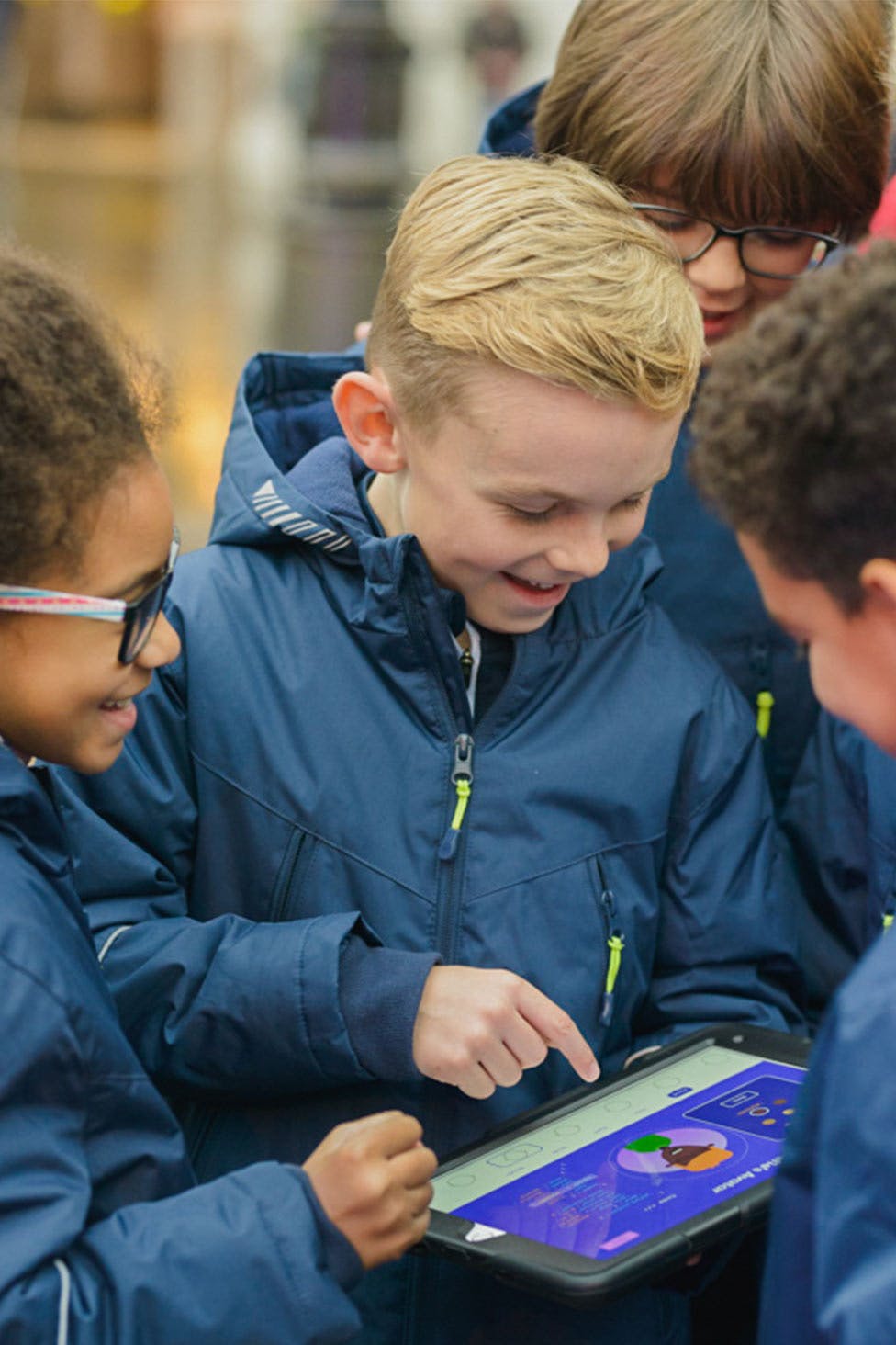 Four young people gathered around an iPad, creating an avatar.