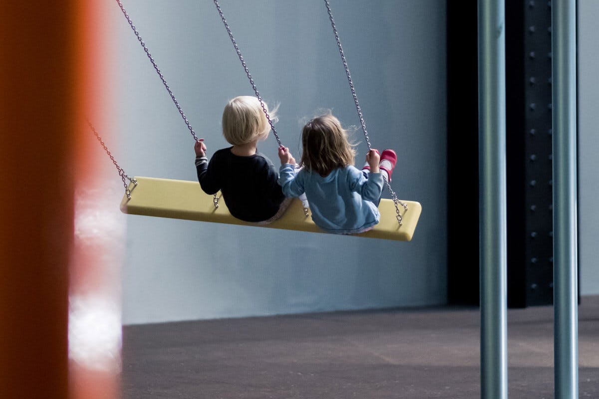 Kinder auf Schaukel am Indoor-Spielplatz