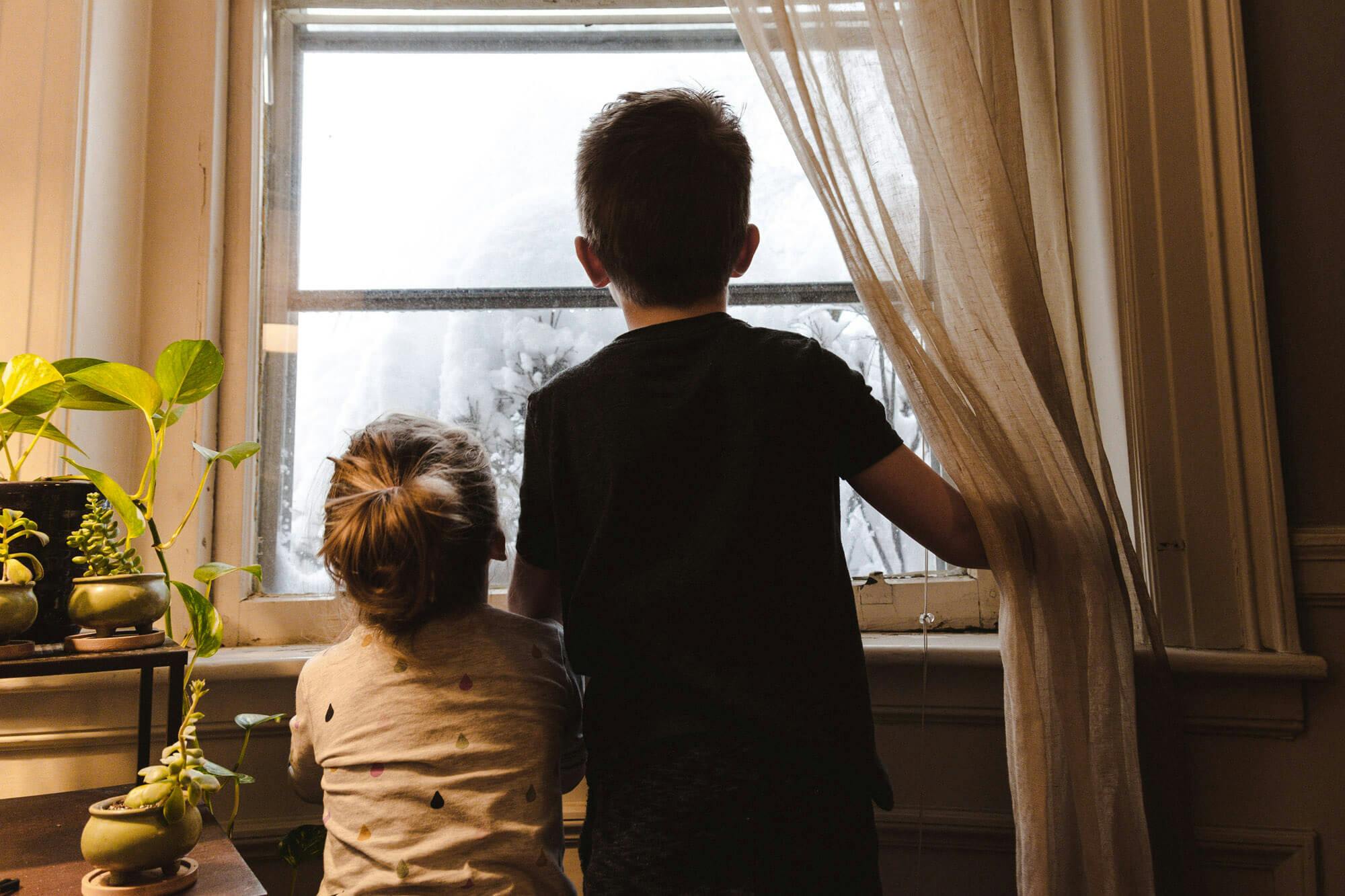 Kinder schauen im Winter aus dem Fenster